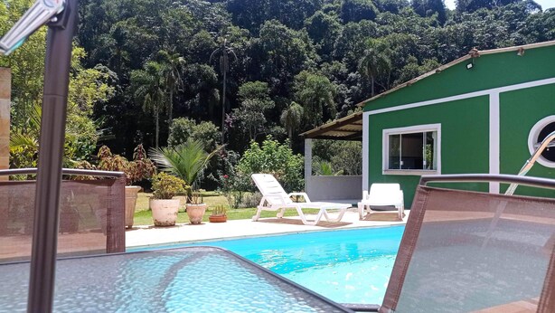 A pool area with lounge chairs and potted plants, surrounded by lush greenery.