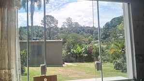 A room with a large sliding glass door leading to a garden with a view of a hill and trees.