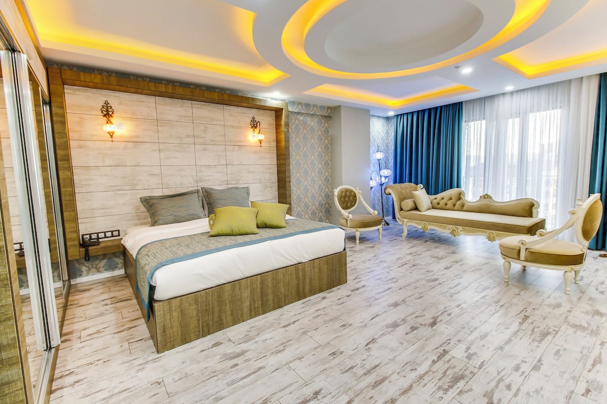 Un dormitorio moderno con una cama grande, un sofá y dos sillones.
