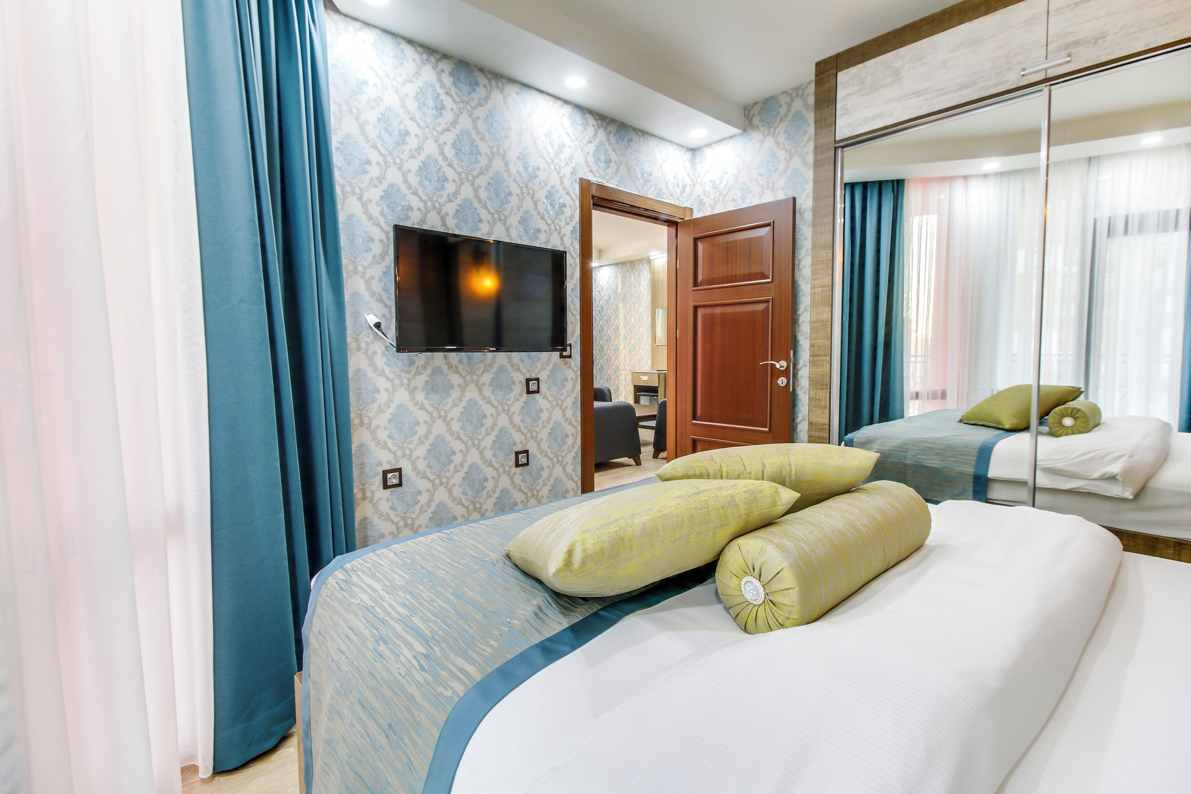 A hotel room with a bed, a TV mounted on the wall, and a mirror.