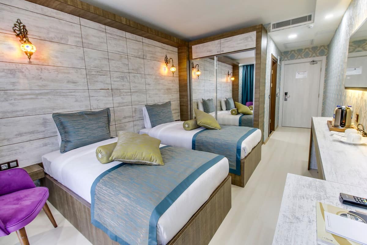Una habitación de hotel con dos camas, un escritorio, una silla y un espejo.
