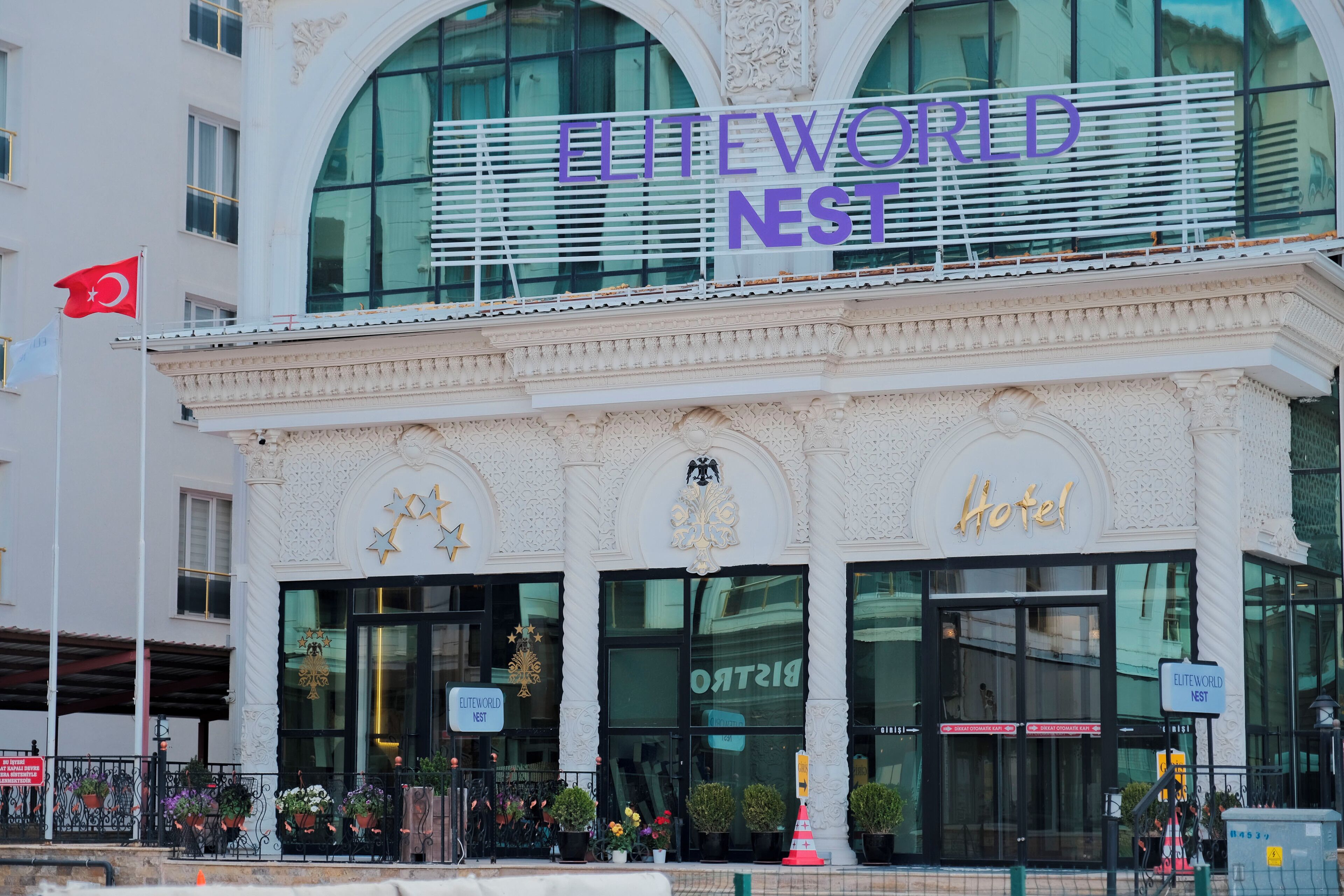 Het uiterlijk van hotel EliteWorld Nest, met een opvallend bord, grote ramen en een vlag.