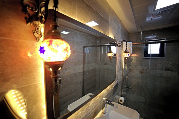 A modern bathroom with a glass shower enclosure, a large mirror, and a white sink.