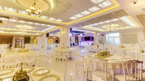 A banquet hall with round tables, white chairs, chandeliers, and ornate ceiling details. - Elite World Nest Sivas (Sivas)