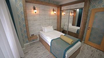 Un dormitorio con cabecera de madera, cama con ropa de cama blanca, mesita de noche y un espejo.
