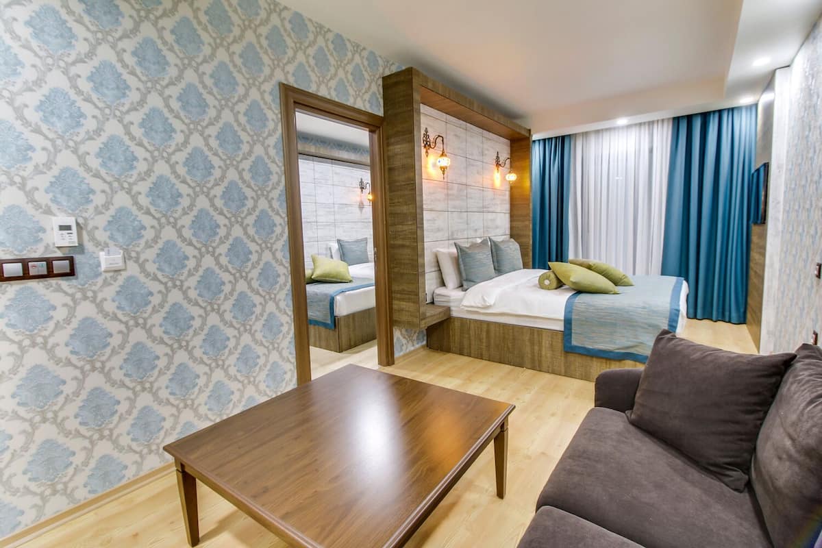 Una habitación pequeña con cama, sofá, mesa de madera y espejo.