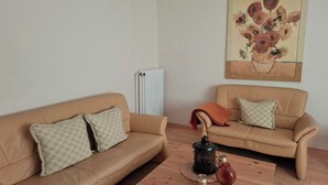 Un soggiorno con due divani color beige, un tavolino di legno e un termosifone.