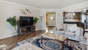 A living room with a TV, sofa, coffee table, and decorative wall piece.