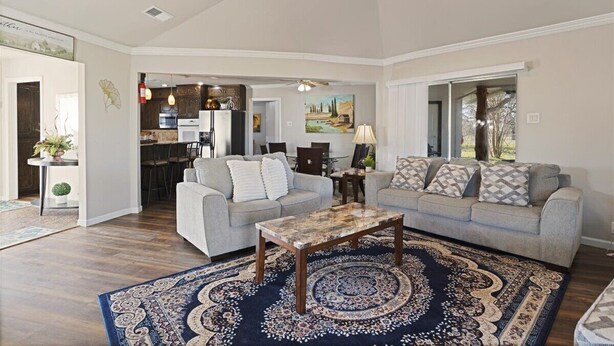 A spacious living room with a grey sofa, a coffee table, and a patterned rug.