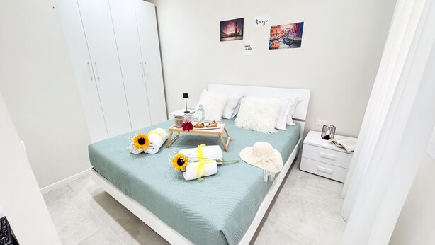 Een keurig opgemaakt slaapkamer met een bed, nachtkastjes en een kledingkast.
