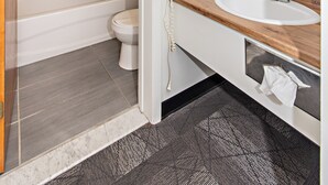 A modern bathroom with a shower, toilet, and sink. - Hôtel Althéa Val-D'Or (Val-d'Or)