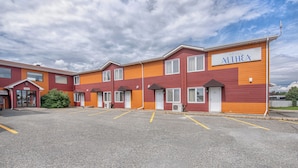 A hotel with a red and orange facade, multiple rooms, and a parking lot. - Hôtel Althéa Val-D'Or (Val-d'Or)