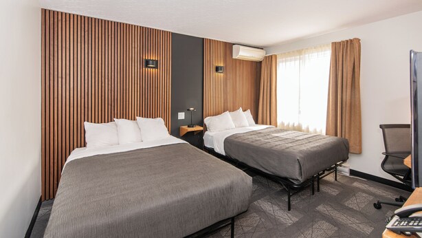 A hotel room with two beds, a desk, a chair, and a TV. - Hôtel Althéa Val-D'Or (Val-d'Or)