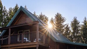 Een houten blokhut met twee verdiepingen, een balkon, een overdekte veranda en een veranda met horreken.