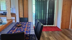 A dining area with a table set for four, a red carpet, and a view through a glass door to an outdoor area. - 4-bedroom house (118, Trois-Rivières,)