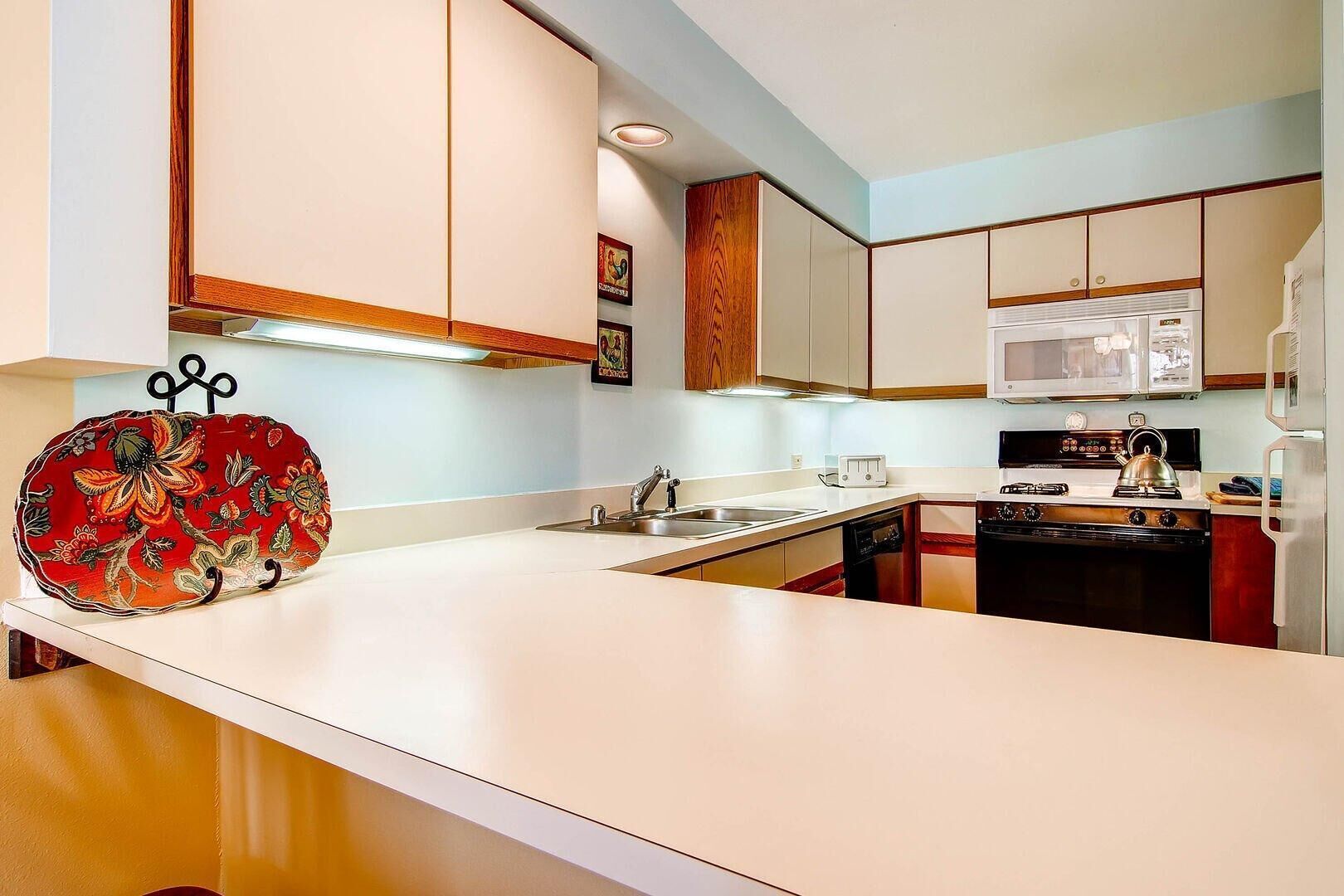A kitchen with white cabinets, a microwave, a stove, and a sink.