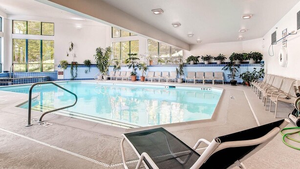 A swimming pool with lounge chairs and potted plants, surrounded by large windows. - Sunrise - W Glade J-1 (Killington)