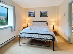 A bedroom with a bed, two bedside lamps, a window with curtains, and two framed pictures on the wall. - Mt Green 2-f06 (Killington)