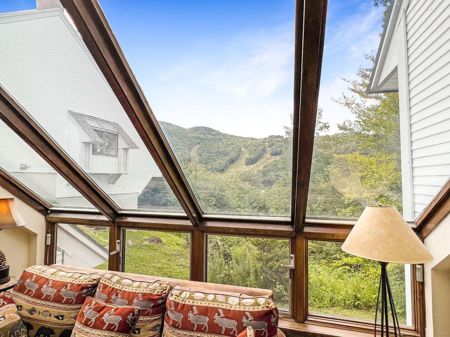 A room with a large skylight, a sofa with patterned cushions, and a lamp.