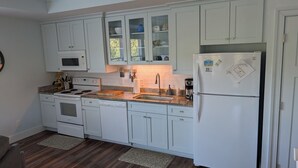 Una cocina moderna con armarios blancos, horno empotrado, lavavajillas, refrigerador y encimera de granito.