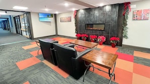 Een vergaderruimte met een grote tafel, diverse stoelen, een open haard en een televisie aan de muur.