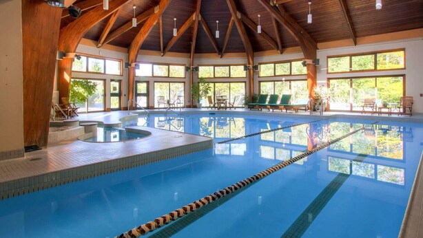 An indoor swimming pool with wooden beams, clear lanes, and sunlit windows. - Woods Village 10 (Killington)