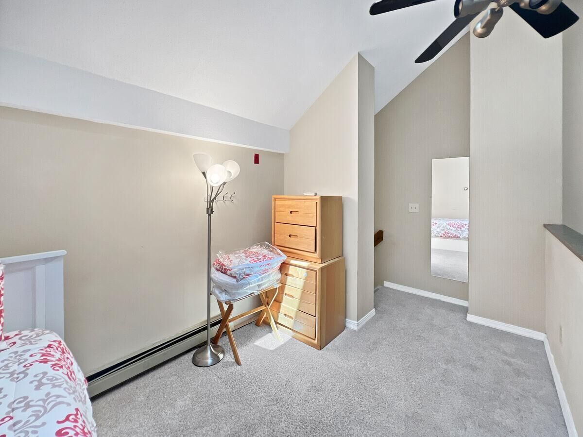 A bedroom with a bed, a dresser, a lamp, and a mirror.