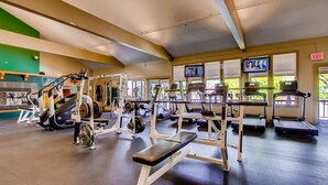 Un gimnasio con diferentes equipos de ejercicio, incluyendo cintas de correr, máquinas de pesas y una banca.