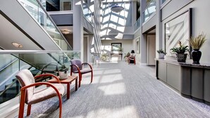 A spacious atrium with a high ceiling, glass railings, and a central staircase. - Woods Village 43 (Killington)