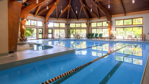 An indoor swimming pool with wooden beams, clear pool lanes, and sunlit windows. - Woods Village 43 (Killington)