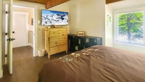 A bedroom with a large bed, wooden dresser, and a television on the wall. - Great Escape Ski Lodge (Killington)