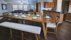 Un coin repas avec une table en bois dressée pour quatre personnes, un banc et un ventilateur de plafond.