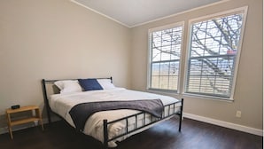 Une chambre à coucher avec un lit, une table de chevet et une fenêtre avec des stores.