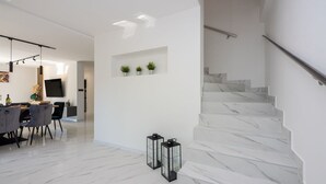 Un intérieur moderne comprenant un escalier, un coin repas et un téléviseur à écran plat fixé au mur.