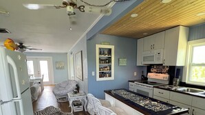 A kitchen with a central island, white cabinetry, a microwave, and a ceiling fan.