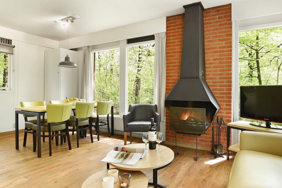A modern living room with a fireplace, dining area, and TV.