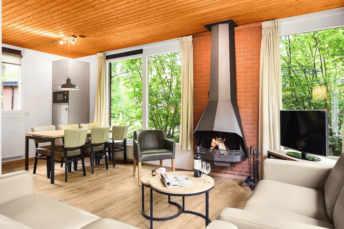 A modern living room with a fireplace, a dining area, and a TV.