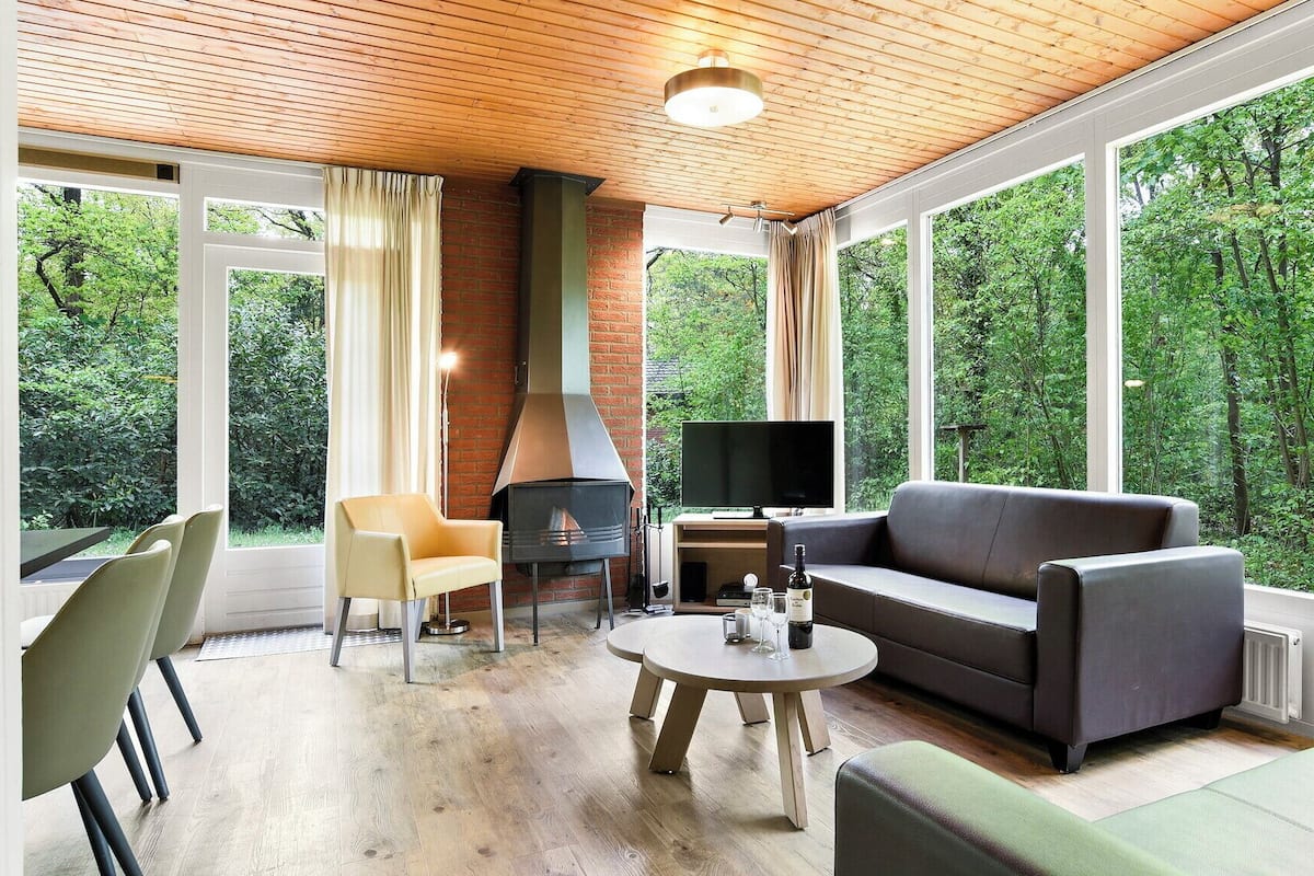A cozy living room with a fireplace, a sofa, a TV, and a dining area with chairs.