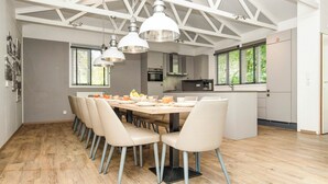 A modern kitchen with a dining area, featuring a large wooden table, beige chairs, and pendant lights. - Summio Parc Heihaas (Putten)