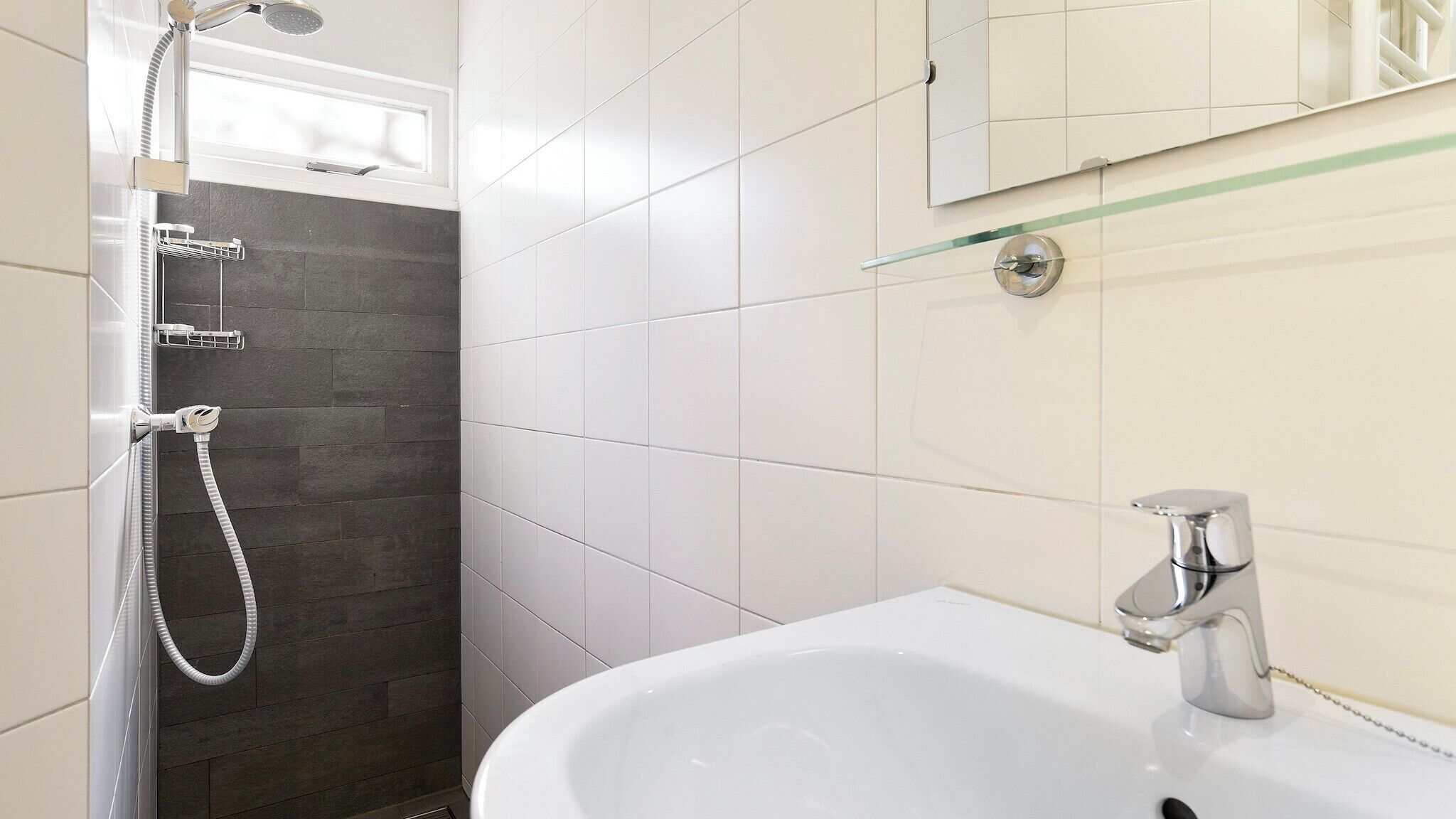 A bathroom with a shower, a sink, and a mirror.