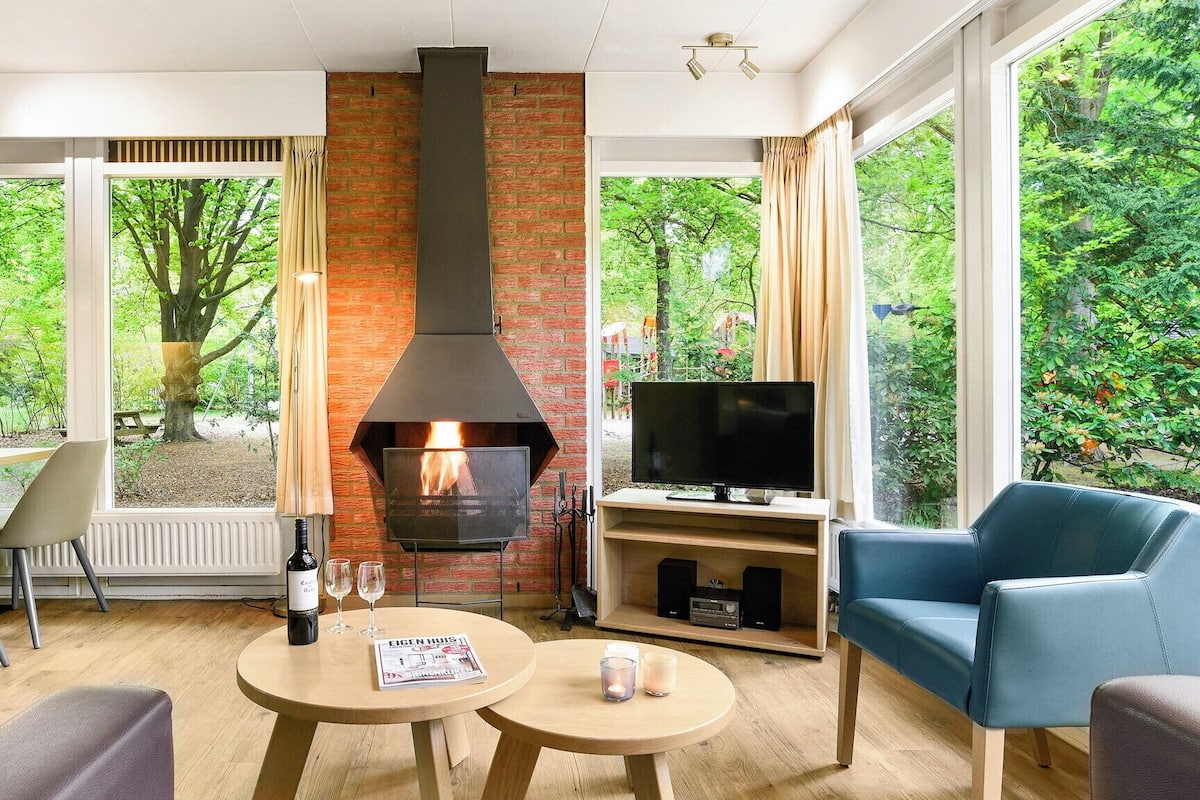 A modern living room with a fireplace, a television, and a dining area with a view of the garden.