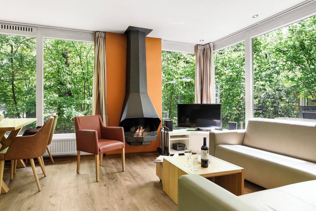 A modern living room with a fireplace, a sofa, a TV, and a dining area with chairs and a table.