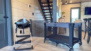 Ein Zimmer mit einer Holztreppe, einem schwarzen Haustiergatter und einem kleinen Tisch mit einer weißen Tasse.