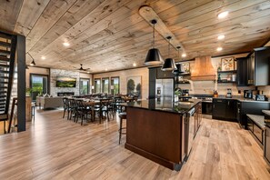A spacious kitchen with wooden flooring, a central island, and modern appliances.