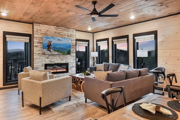 A modern living room with a fireplace, comfortable seating, and large windows offering scenic views.