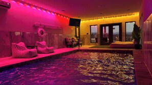 Un espace bien-être comprenant un jacuzzi, des sièges et un téléviseur.