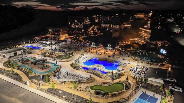 Vista aérea de un complejo turístico con múltiples piscinas, un campo de golf y un amplio estacionamiento.