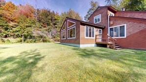 A modern wooden house with a large front yard and a staircase leading to the entrance. - The Maple Leaf (Killington)