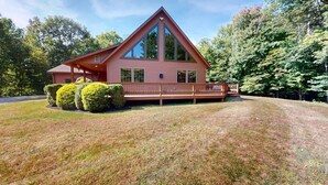 A large, single-story cabin with a prominent triangular roof, a covered porch, and a well-maintained lawn. - Beechwood Home (Rutland)