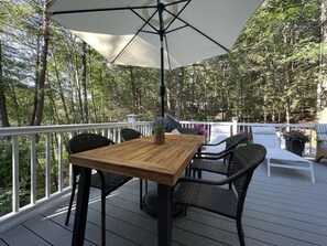 A wooden deck with a table and chairs, surrounded by a white railing and trees. - Harbor Hideaway (York)